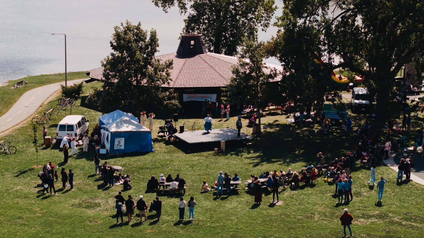 Drone aerial view of the full Good Neighbor Gathering event at Brittingham Park beside the lake
